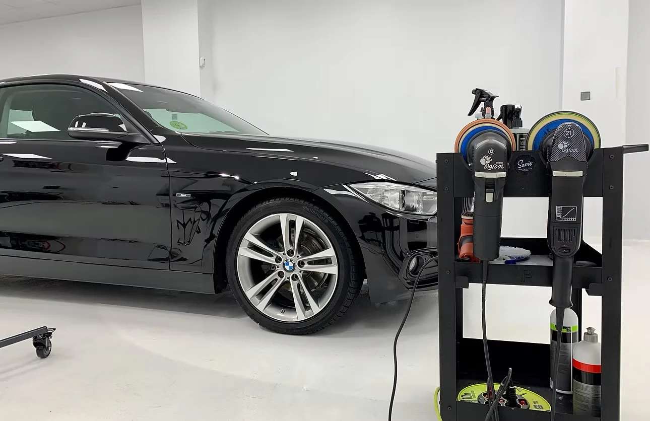 BMW negro pulido junto al carro de pulidoras